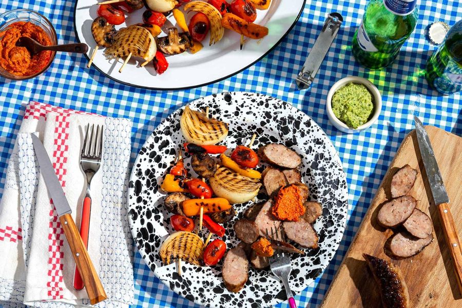 Italian sausages and vegetable skewers with two romescos