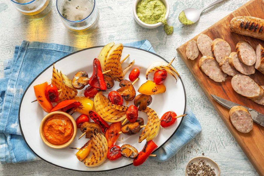 Italian sausages and vegetable skewers with two romescos