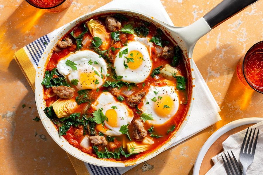 Sausage shakshuka with eggs, artichoke hearts, and kale