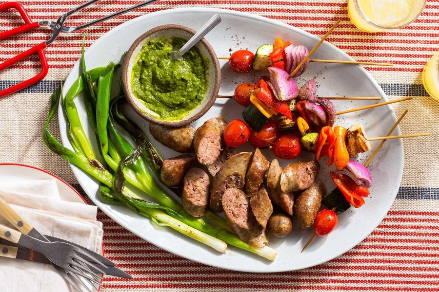 Italian sausages with vegetable skewers and spicy green harissa