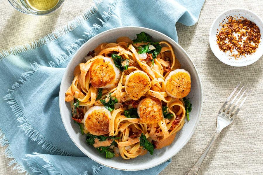 Sea scallops over fresh fettuccine, sun-dried tomatoes, and spinach