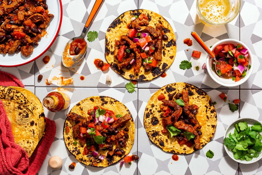 Spicy tinga tacos with black beans and pico de gallo