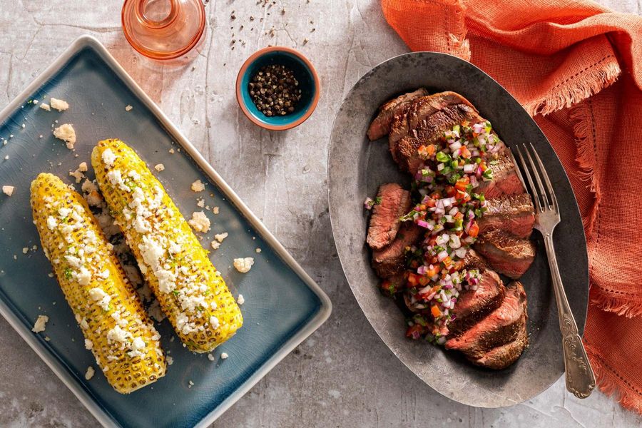 Garlic-marinated steaks with Mexican street corn and salsa cruda