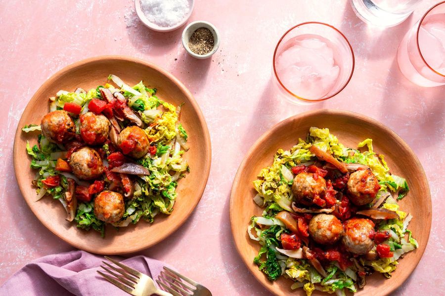 Meatballs with mushroom ragù over wilted cabbage
