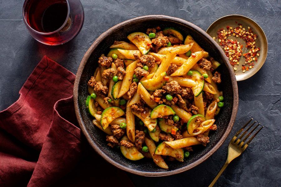 Bolognese with penne rigate, zucchini, and peas