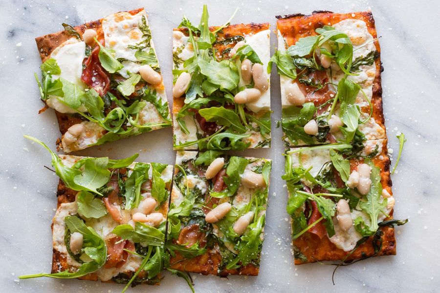 Prosciutto flatbread pizzas with mozzarella, white beans, and arugula