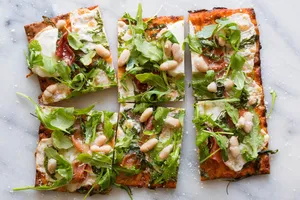 Prosciutto flatbread pizzas with mozzarella, white beans, and arugula