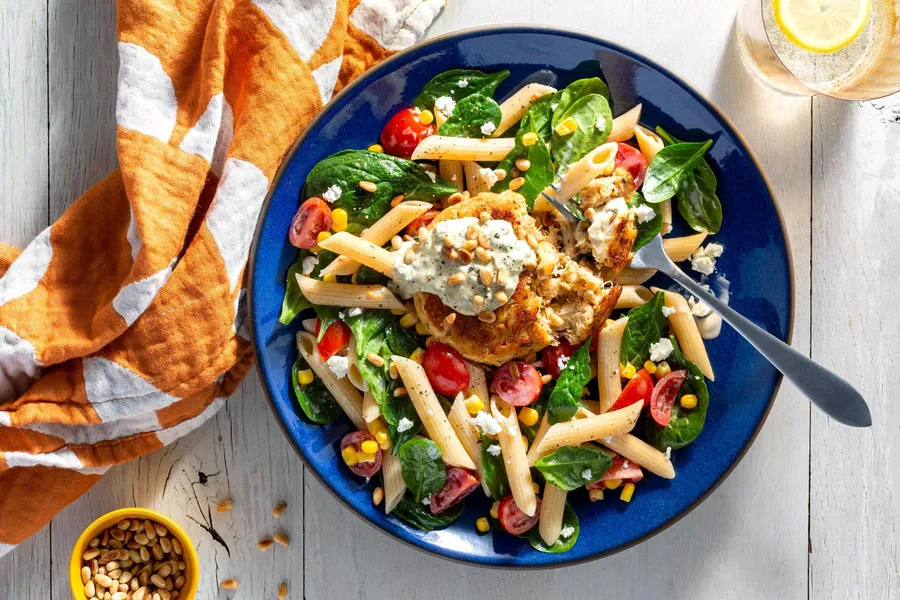 Crab cakes over primavera pasta salad with rémoulade and pine nuts