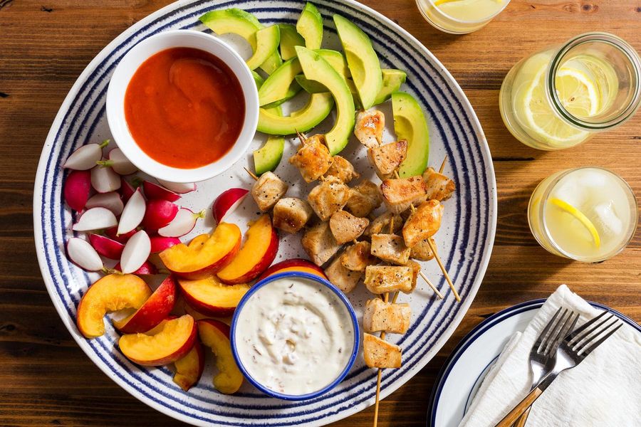 Easy chicken skewers with sliced stone fruit, avocado, and dips