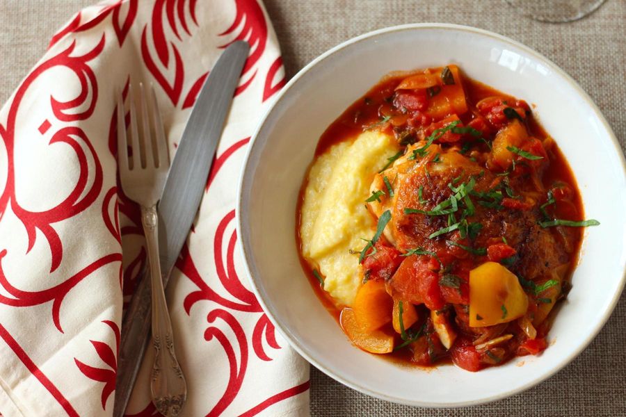 Chicken thighs in tomato sauce with fresh herbs and cheese polenta