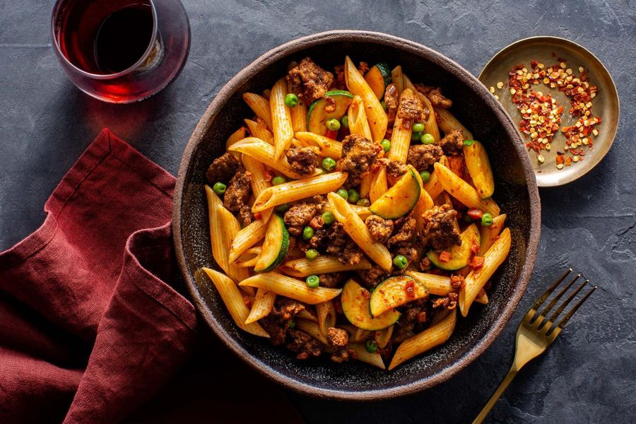 Bolognese with penne rigate, zucchini, and peas