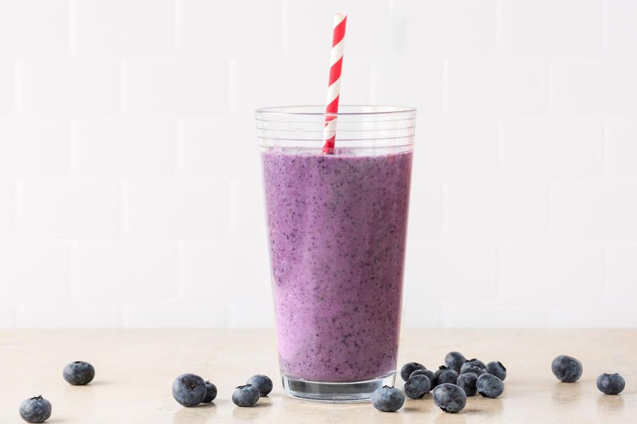 Image of a glass of Mojo Maker smoothie and a scattering of blueberries