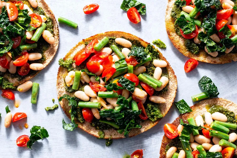 Mediterranean two-bean pitas with tomatoes, basil pesto, and kale salad