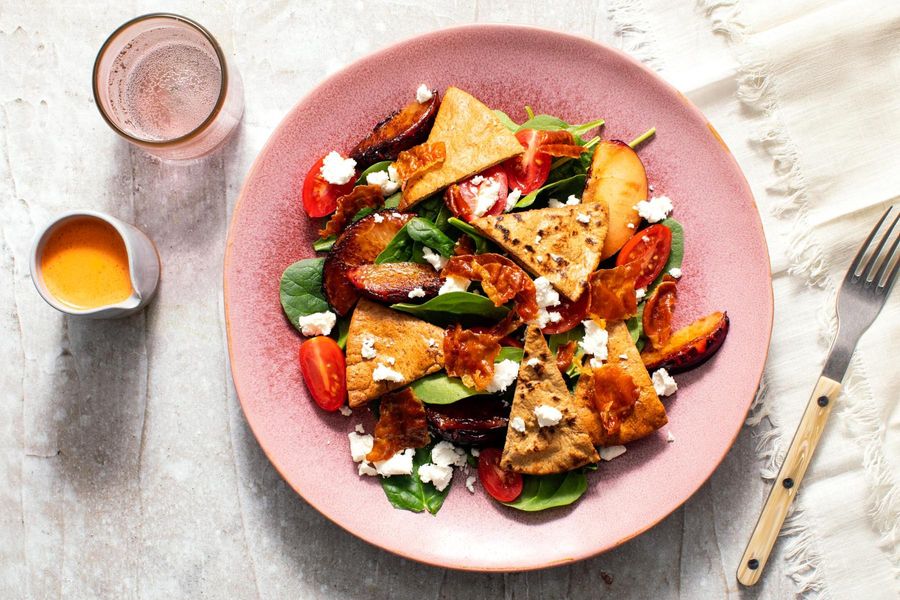 Spinach salad with crisp prosciutto, seared plum, and toasted pita