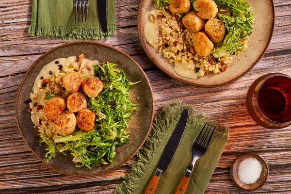 Wild sea scallops over couscous with citrus beurre blanc and frisée salad