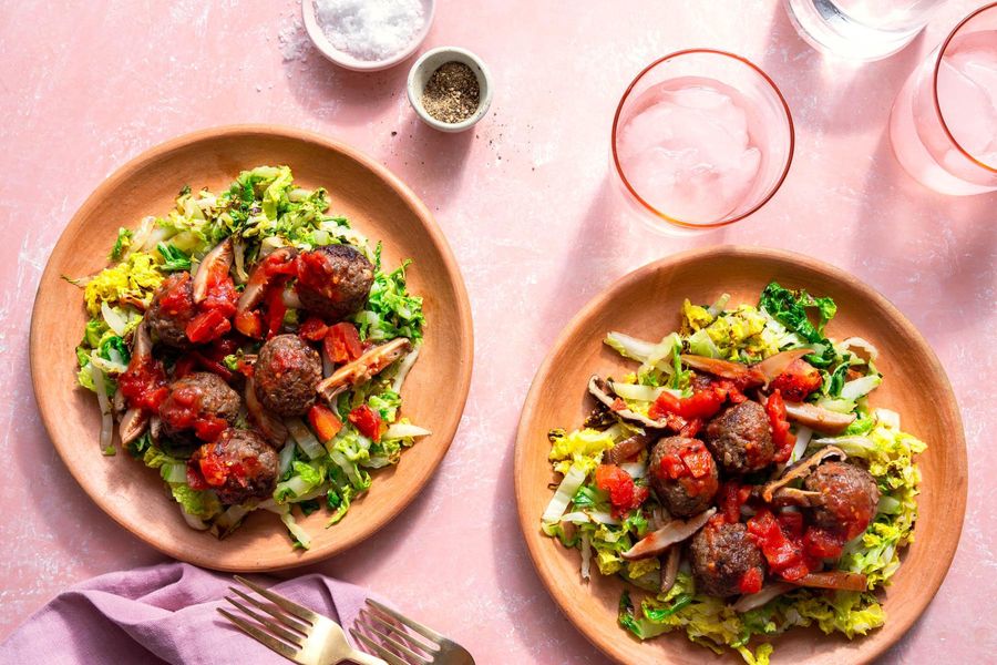 Meatballs with mushroom ragù over wilted cabbage