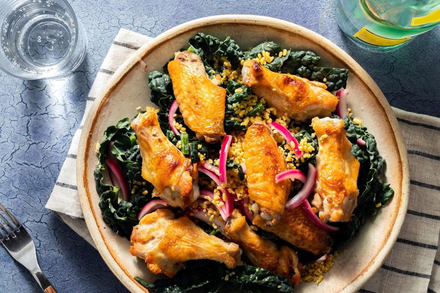 Lemon-pepper chicken wings over freekeh, kale, and pickled onion salad