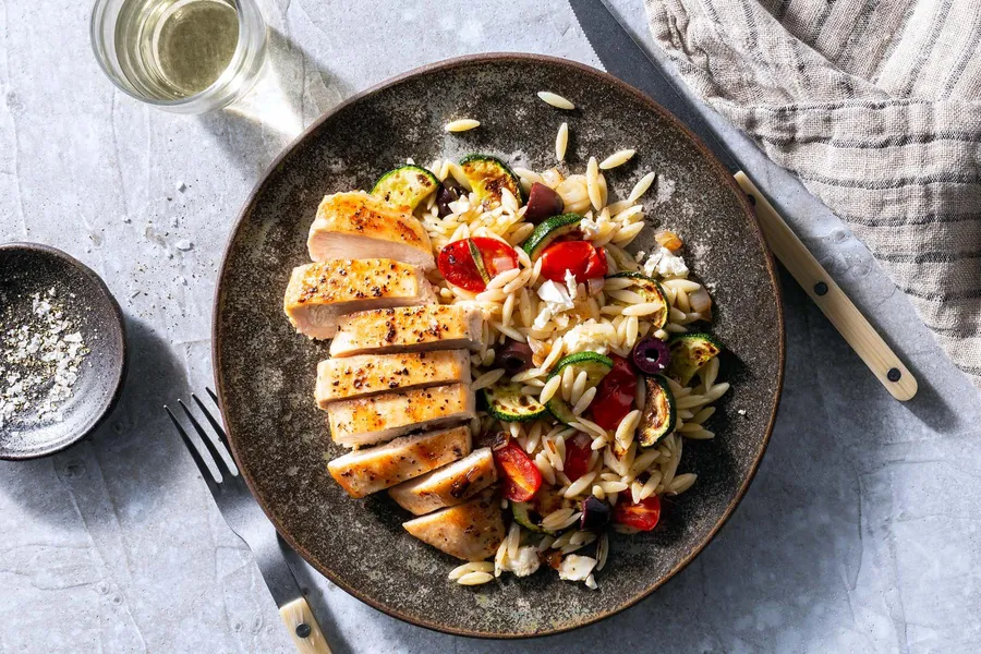 Chicken breasts and Greek orzo salad with tomatoes, olives, and feta